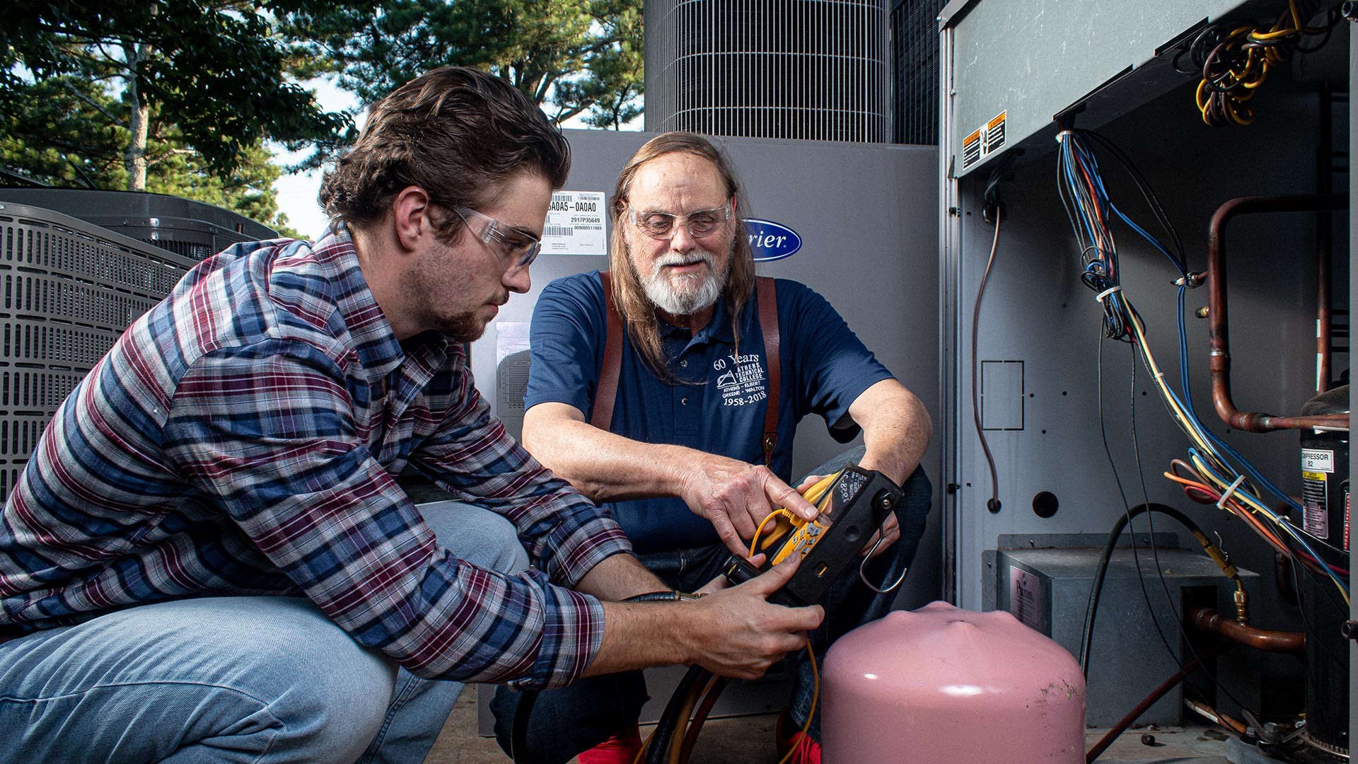 Student and teacher outside working on open a/c unit