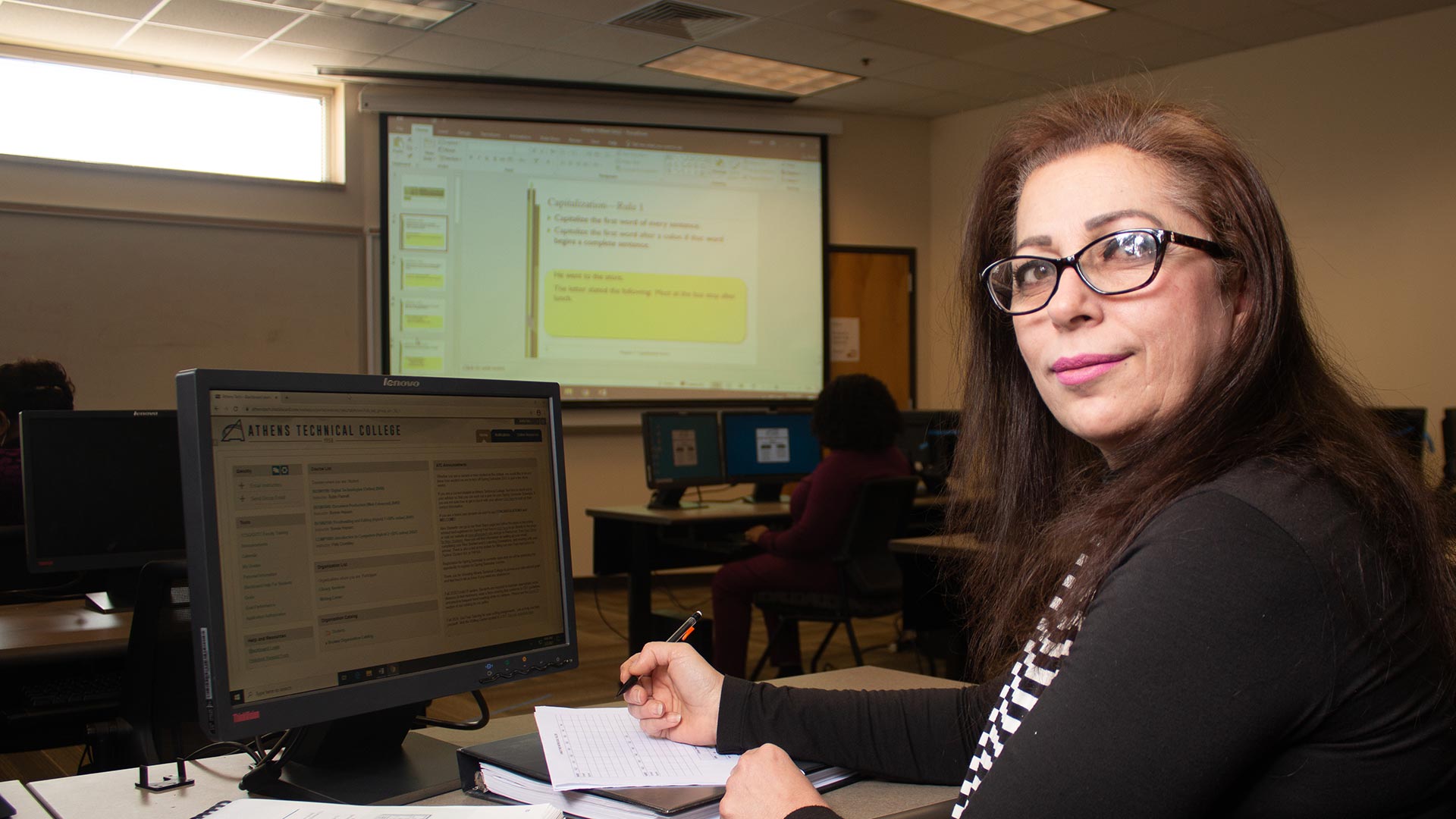 Business management student taking notes and looking at camera