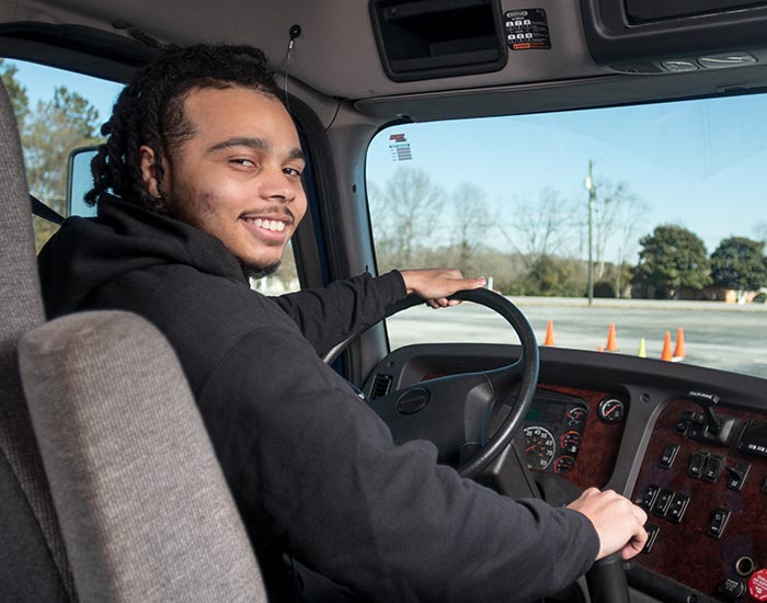 Commercial truck driving student posing in cabin of truck