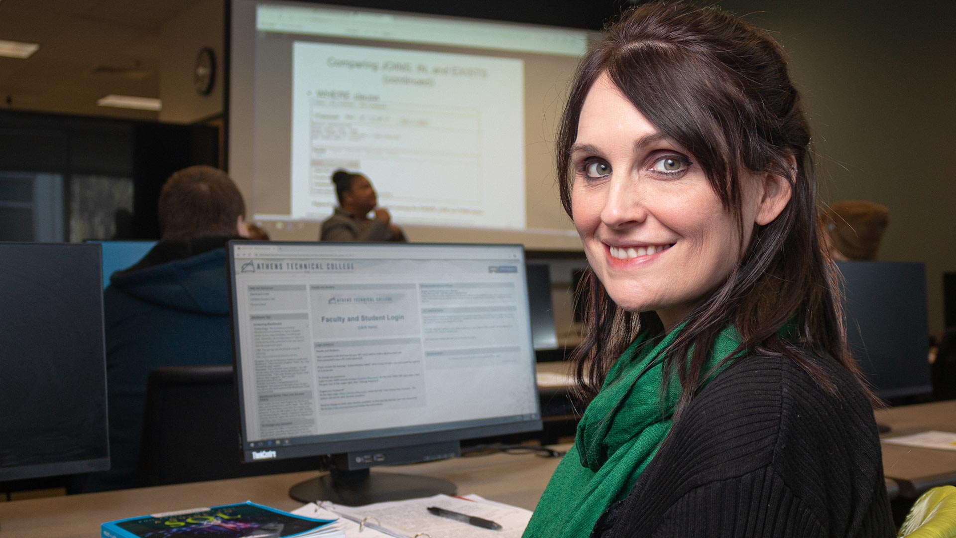 Student smiling at desk while presentation is going on