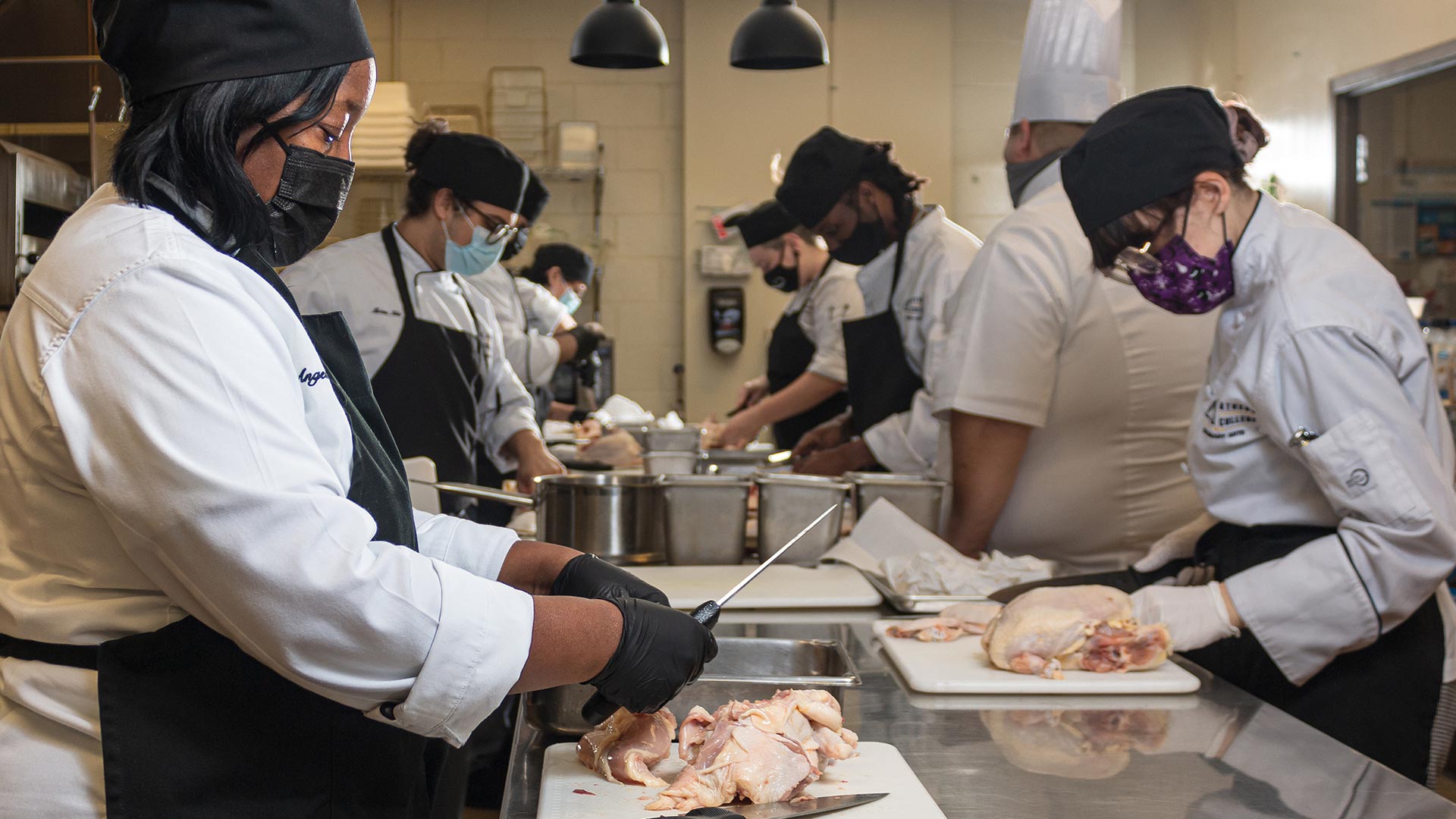 Culinary arts students breaking down chickens