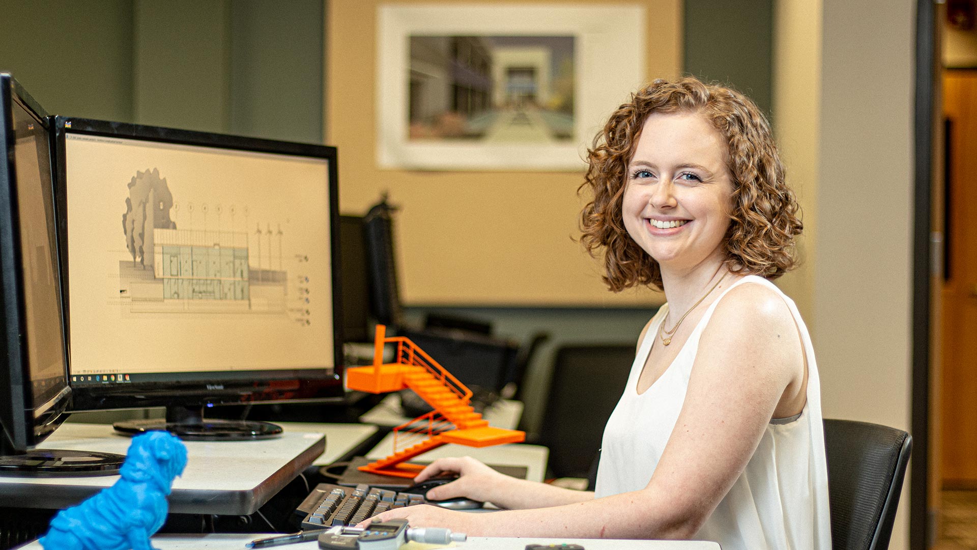 female student working at desk with orange staircase on desk