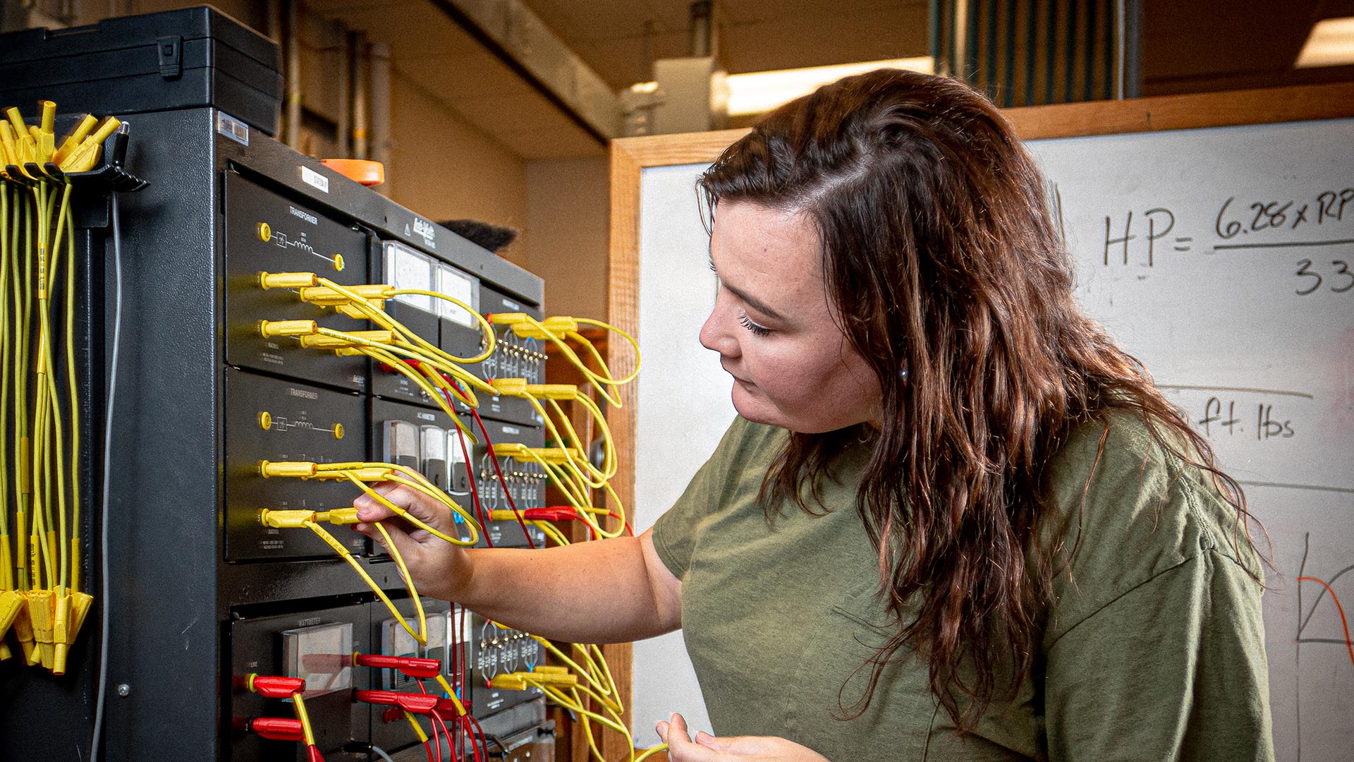 Female student plugging in cable for electrical construction