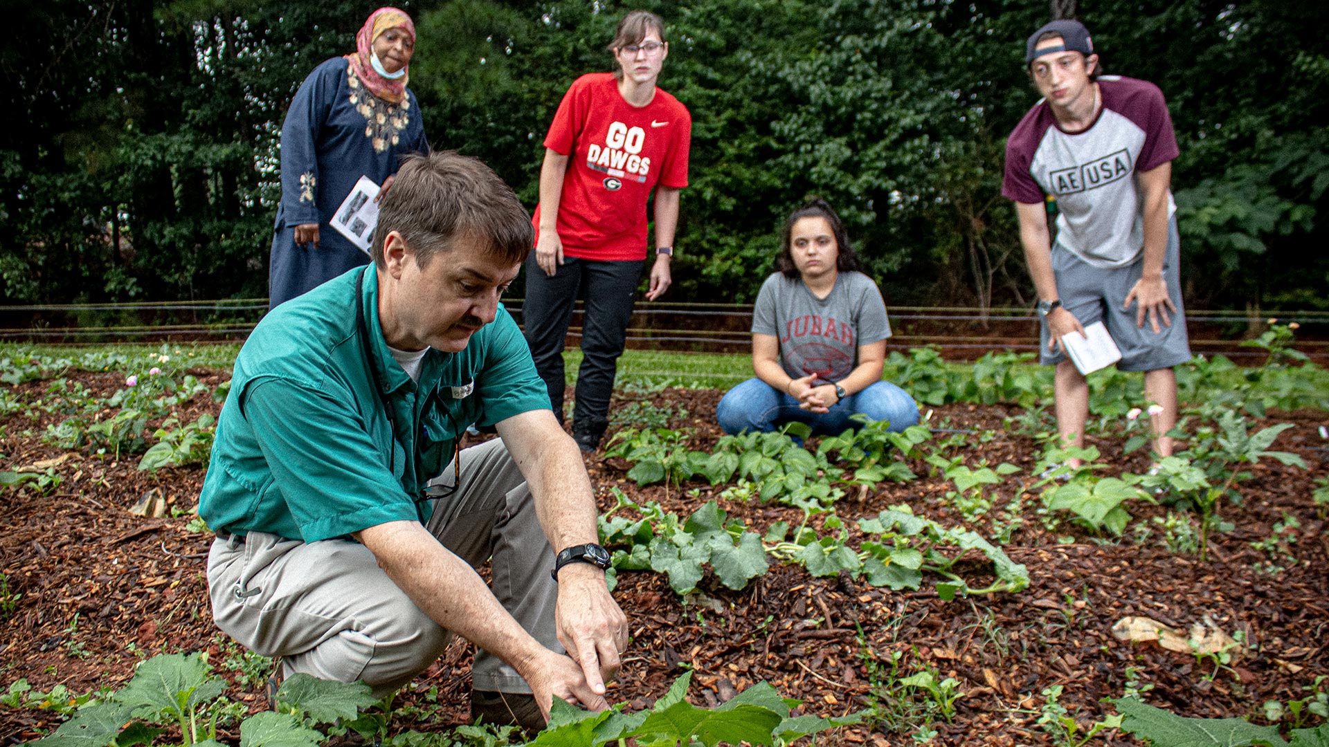 Agriculture students observing professor in field