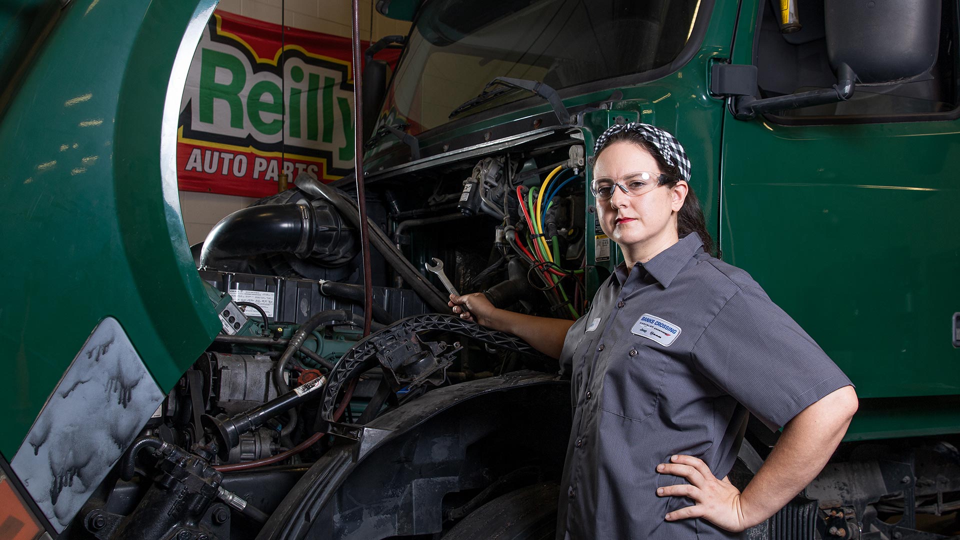 Female student with 18 wheeler, open hood - automotive tech