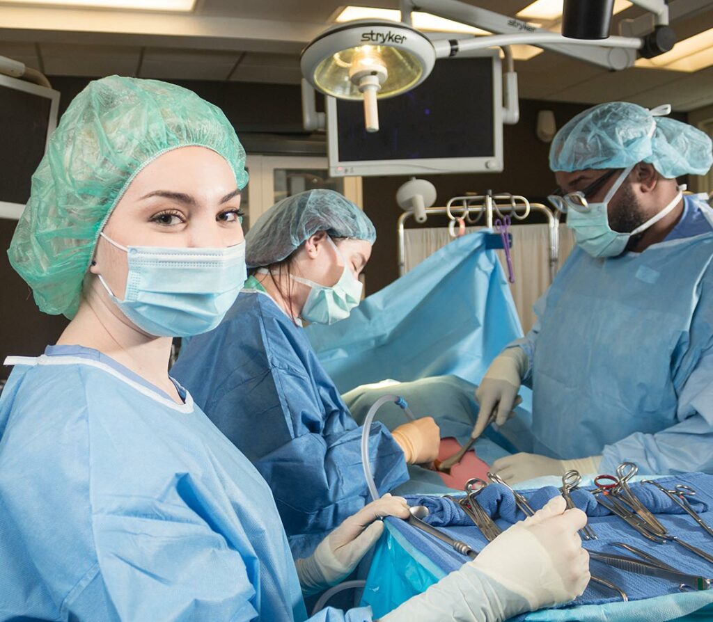 Surgical Tech students in scrubs practicing on a dummy