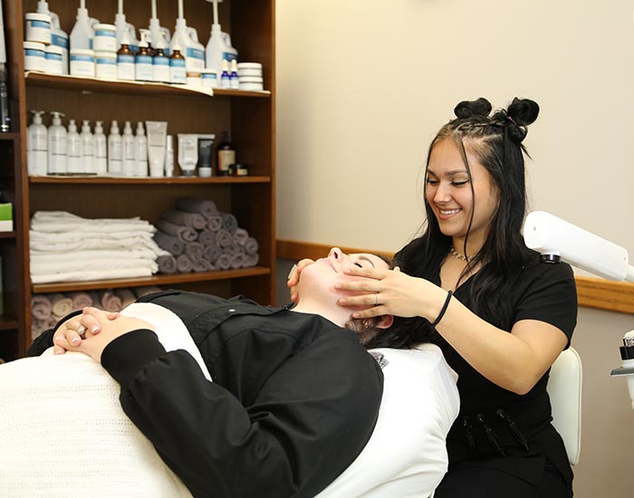 Female student giving another student a facial massage