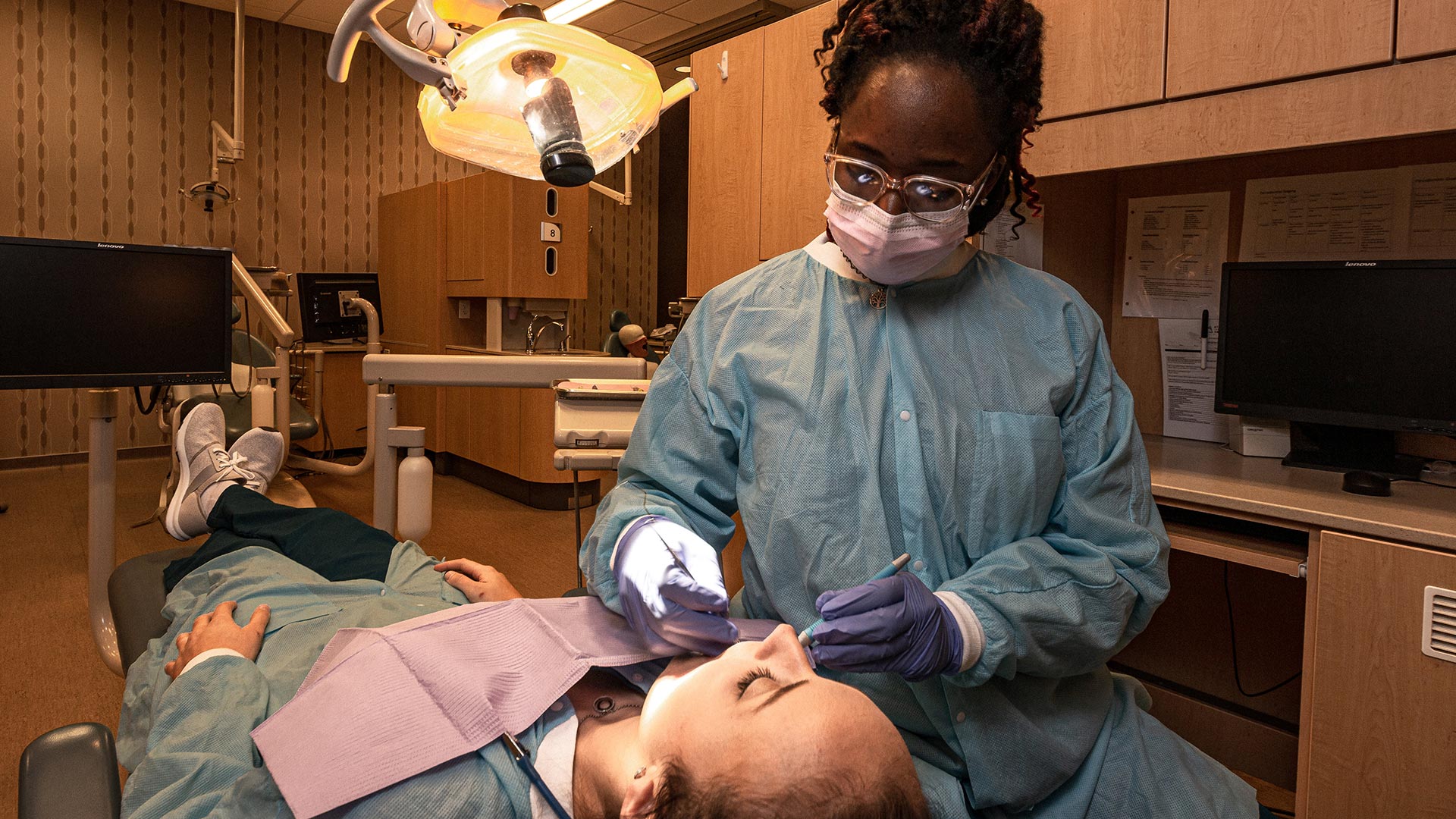 Female dental student cleaning another students teeth