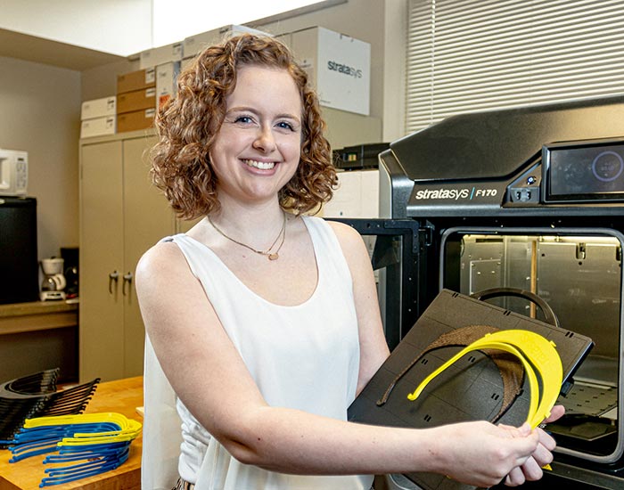 Female student showcasing mold in front of stratasys machine