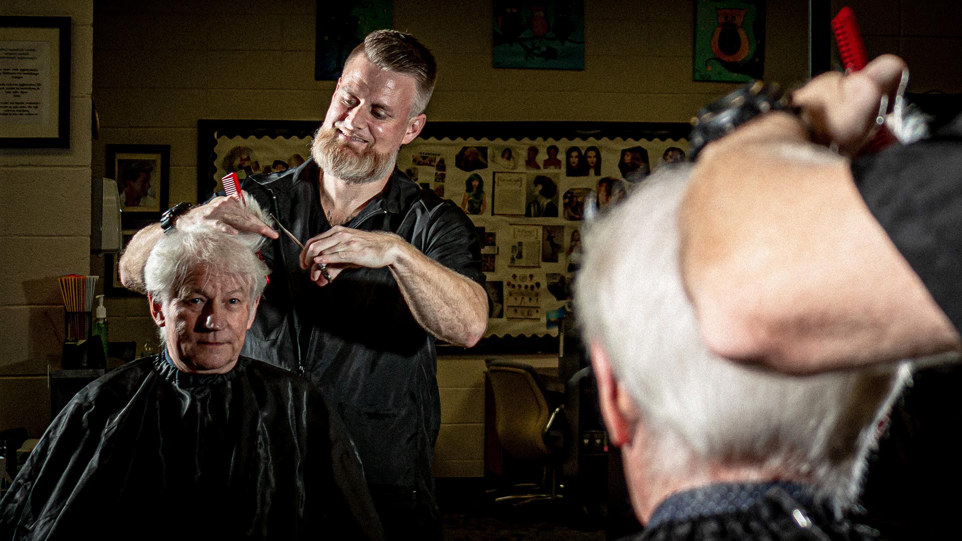 Male student cutting older gentleman's hair