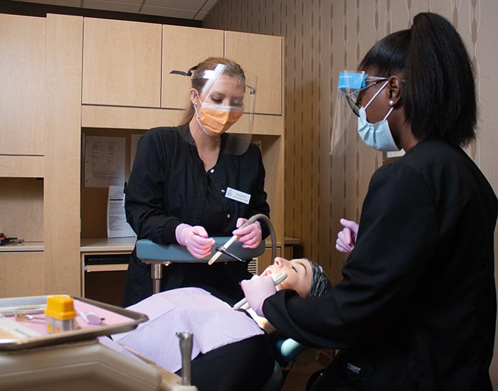 student acting as a dental assisitant working on persons mouth