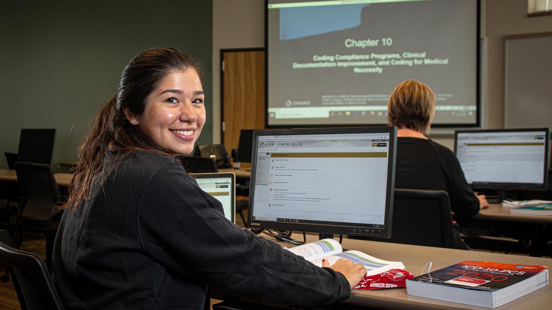 Female student looking back over her shoulder while working on computer