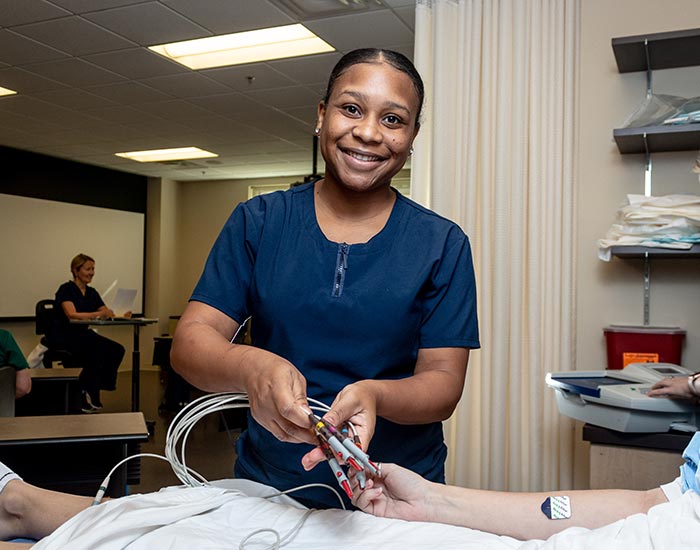 female student checking someone in hospital bed vitals