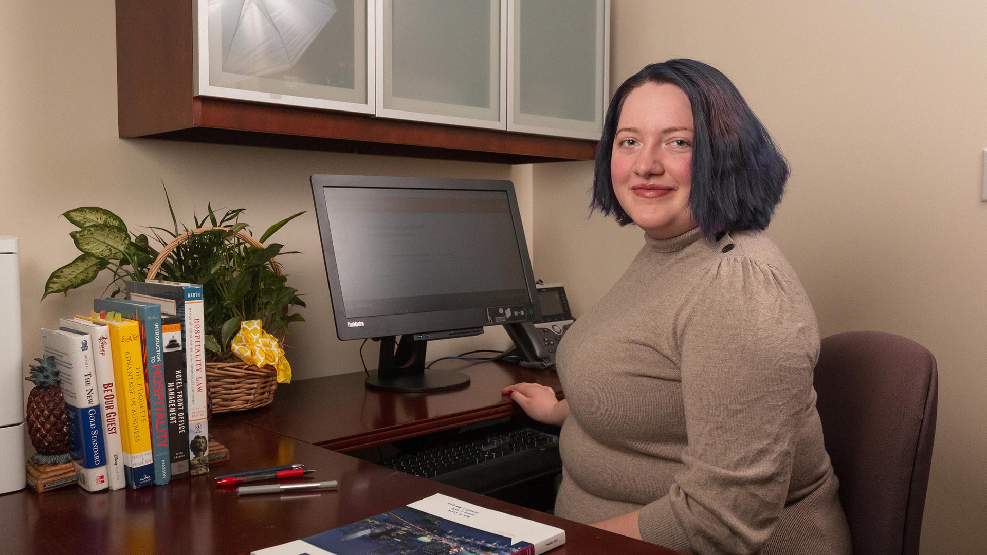 Hotel/Tourism management female student at desk in office looking at camera