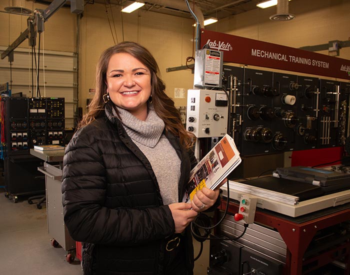 Female standing in a shop with a binder - industrial systems tech