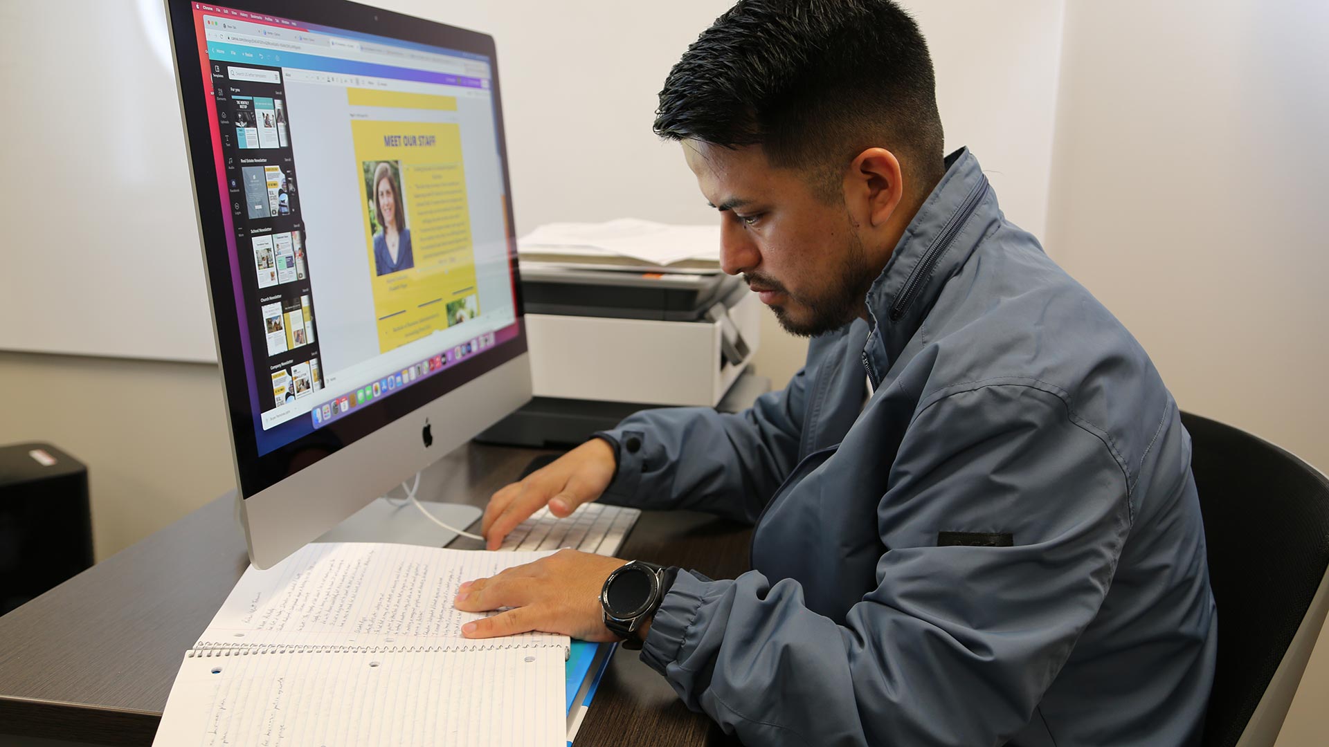 Male marketing student reading his notes and working on computer