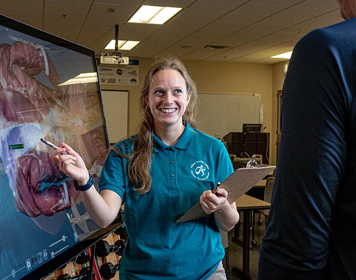 Student going over visual on screen of human body while holding clipboard