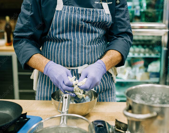 Chef working w food while wearing gloves - serve safe